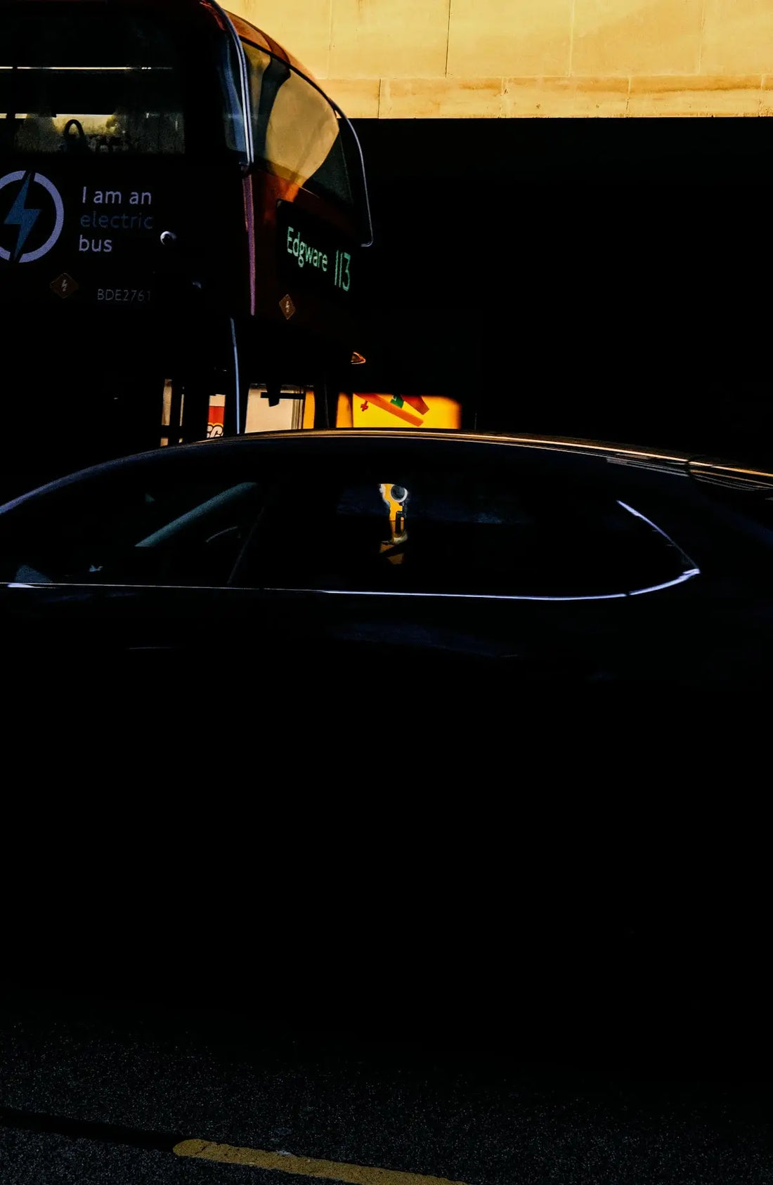 a black car parked next to a double decker bus