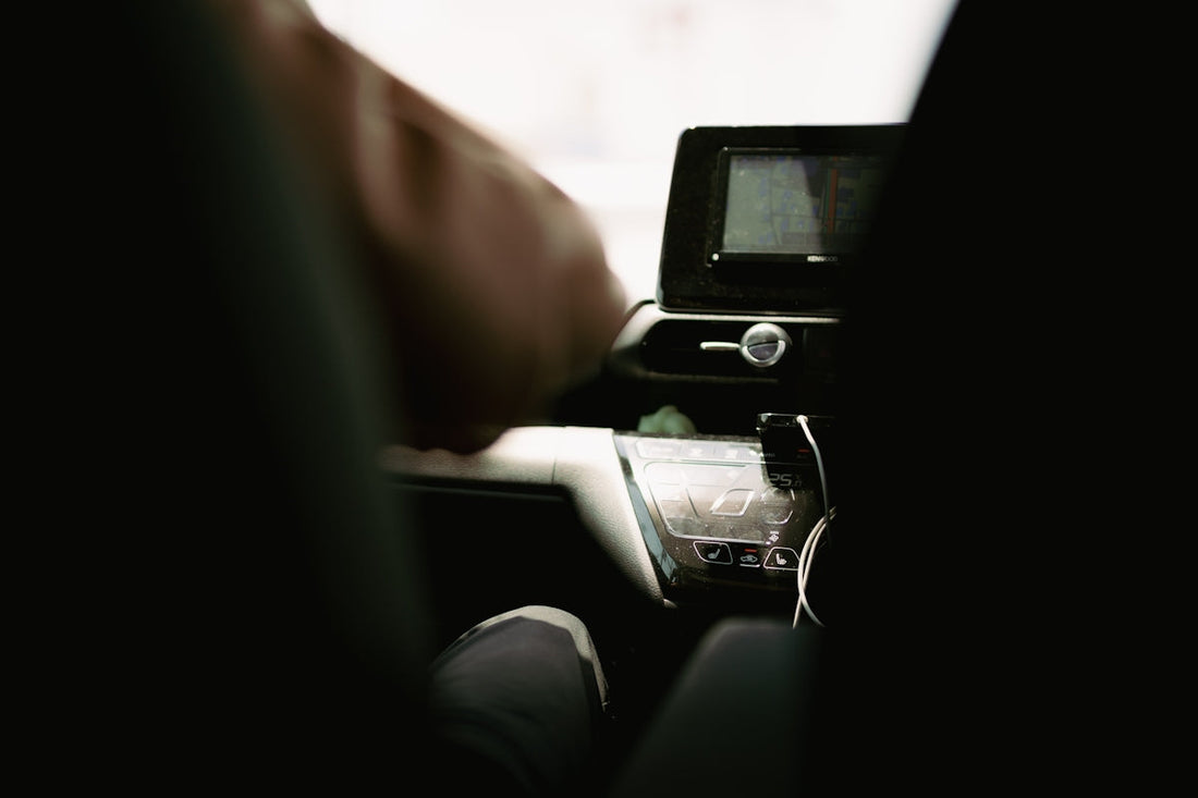 a person sitting in a car with their hand on the steering wheel