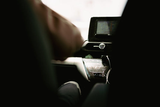 a person sitting in a car with their hand on the steering wheel
