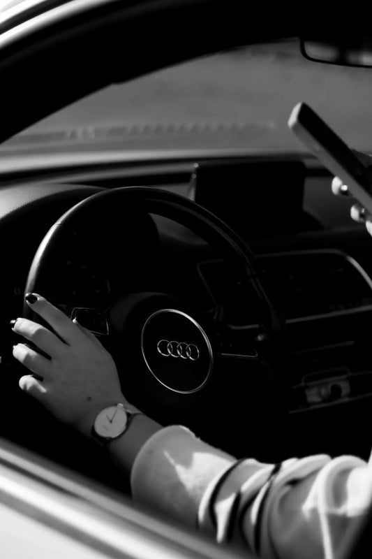 a person driving a car with their hand on the steering wheel