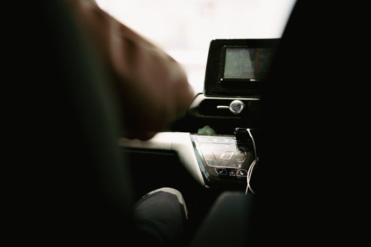 a person sitting in a car with their hand on the steering wheel