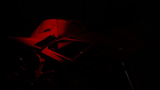 A red light shining on a motorcycle in the dark