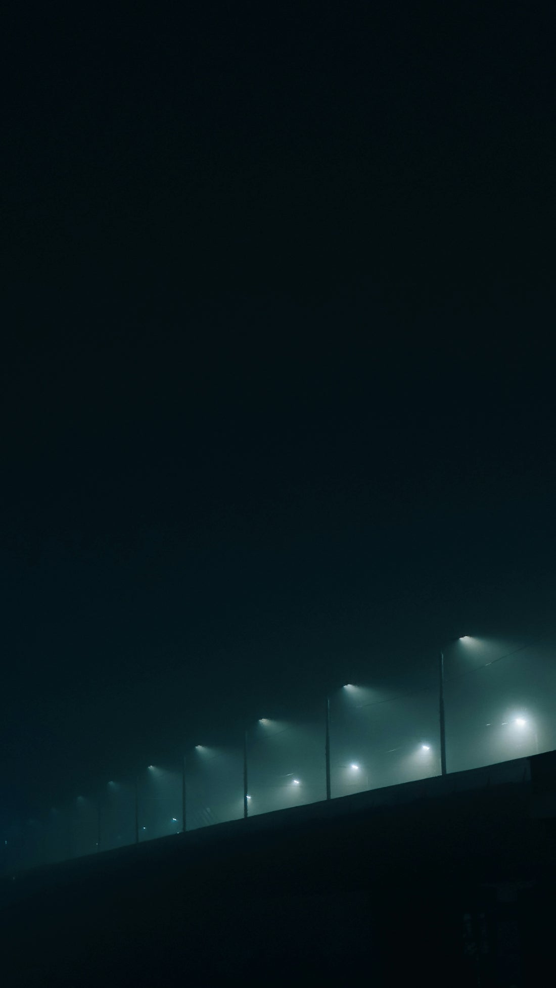 A foggy night with street lights on a bridge
