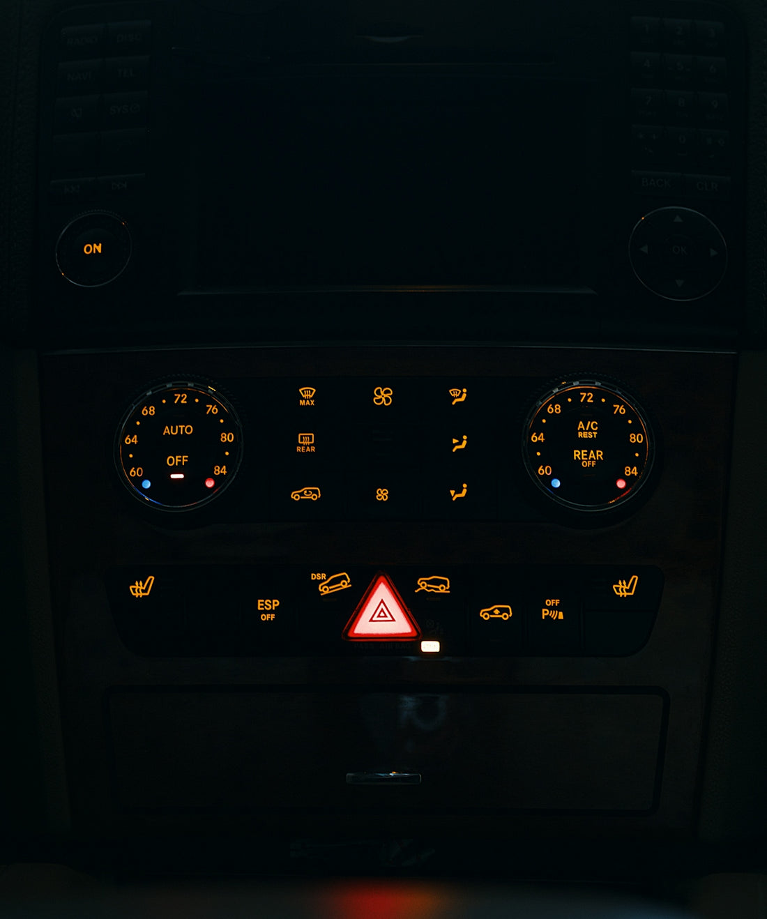 Dashboard controls of a vehicle illuminated at night.