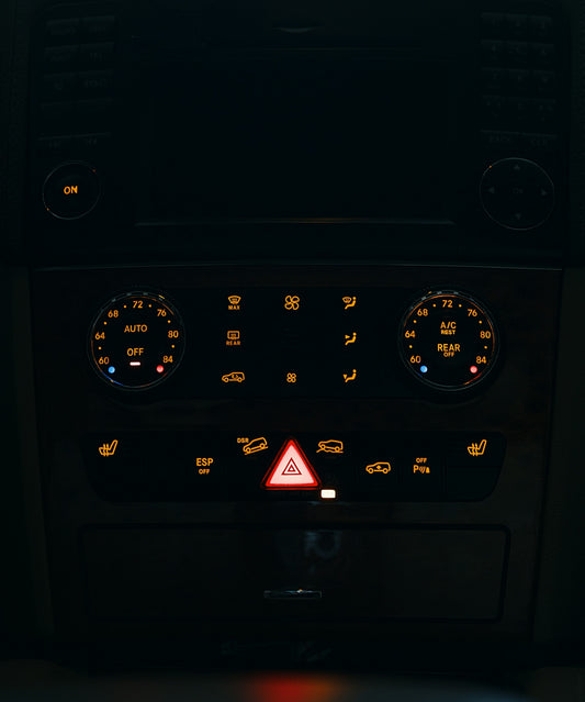 Dashboard controls of a vehicle illuminated at night.