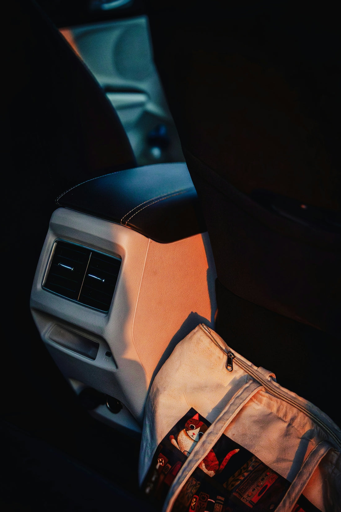 Car's back seat with a bag and sunset light.