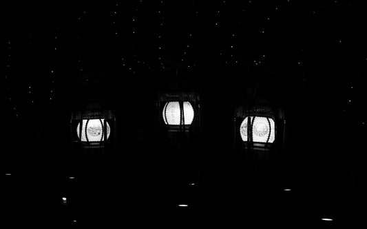 a black and white photo of three windows in a dark room