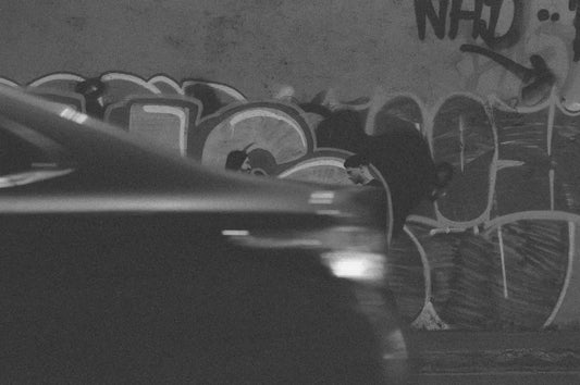 Car passes graffiti on a wall.