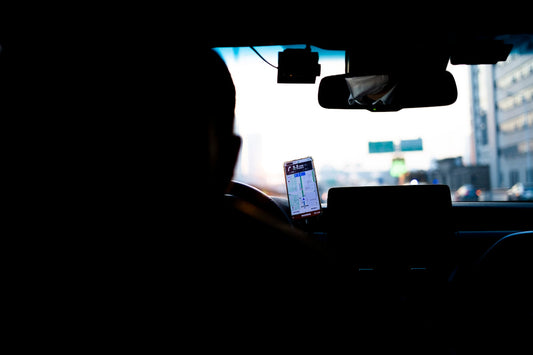a person sitting in a car using a cell phone